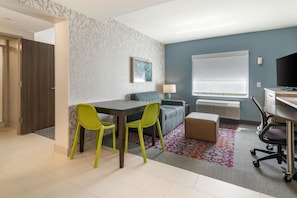 Ein modernes Zimmer mit Essbereich, einer Couch, einem Fernseher und einem Schreibtisch.