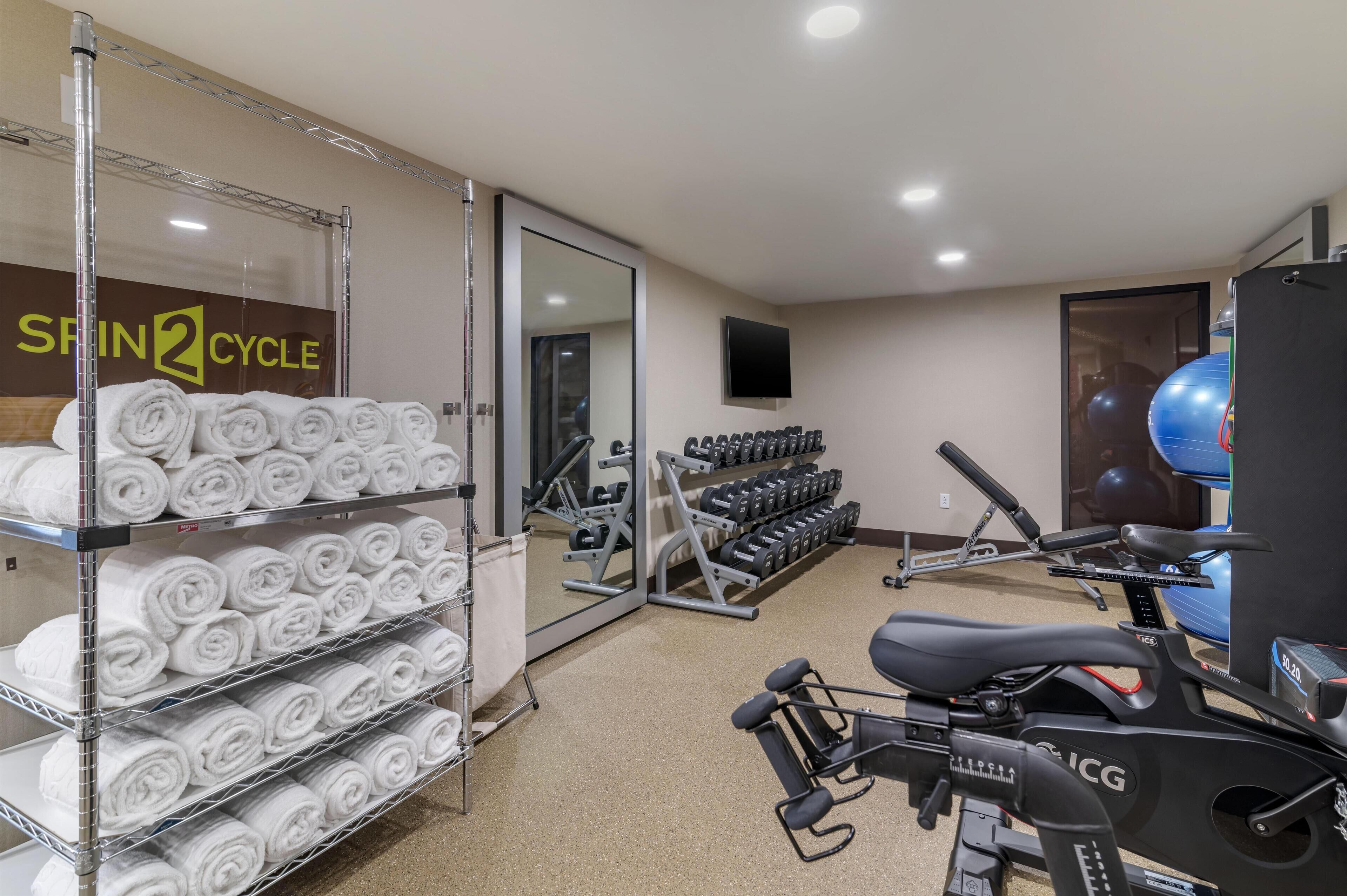 A gym with exercise equipment, towels, and a mirror.