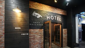 Entrada de un hotel con un letrero que dice "TWENTYS EIGHT HOTEL" y una flecha indicando la entrada.