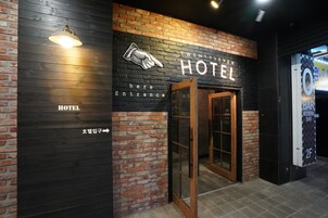 Entrada de hotel com uma placa indicando "TWENTYS EIGHT HOTEL" e uma seta apontando para a entrada.