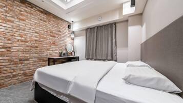 A modern bedroom with a brick wall, a skylight, a bed, a bedside table, and a mirror.