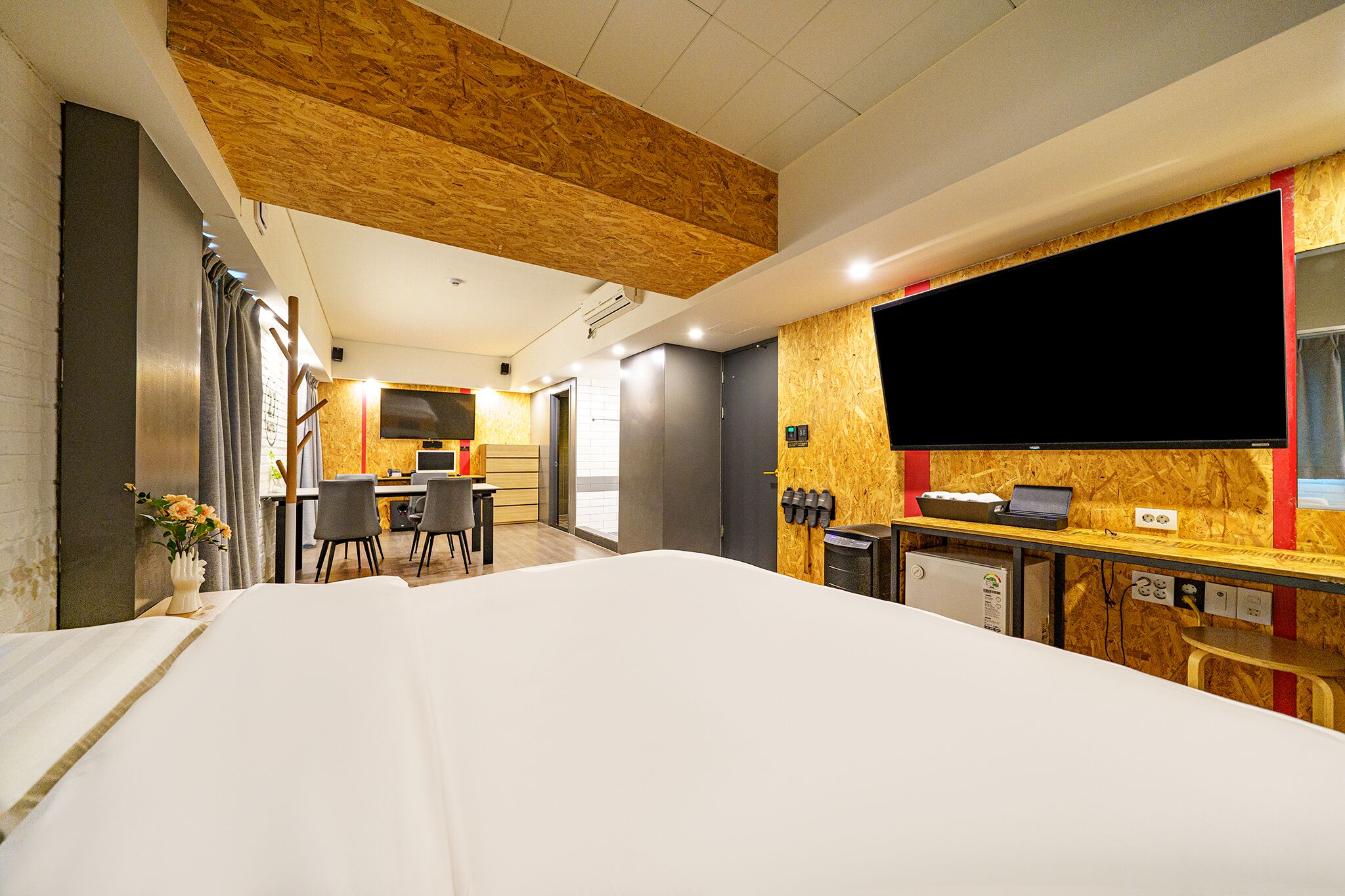 A hotel room with a large bed, a desk with a computer, a chair, and a small table.