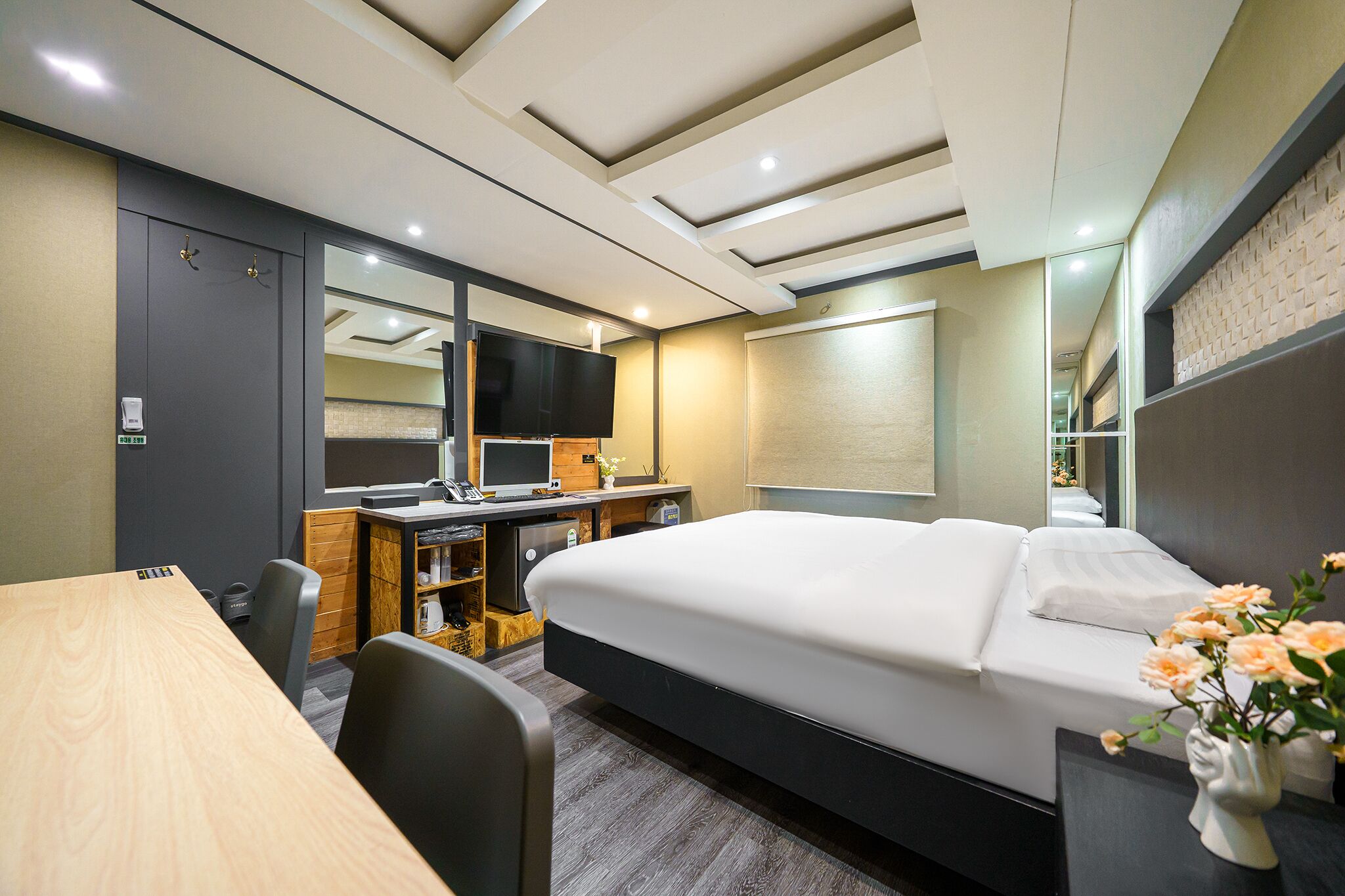 A hotel room with a bed, desk, chair, and a television.