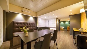 Una sala de conferencias moderna con una mesa larga, asientos cómodos, una pequeña kitchenette y un área de ducha.