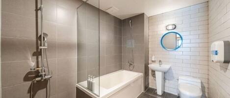 Une salle de bain moderne équipée d’une baignoire, d’une douche, d’un lavabo et de toilettes.