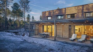 Une maison moderne en bois dotée d’une terrasse, d’un coin repas et d’une cuisine ouverte.