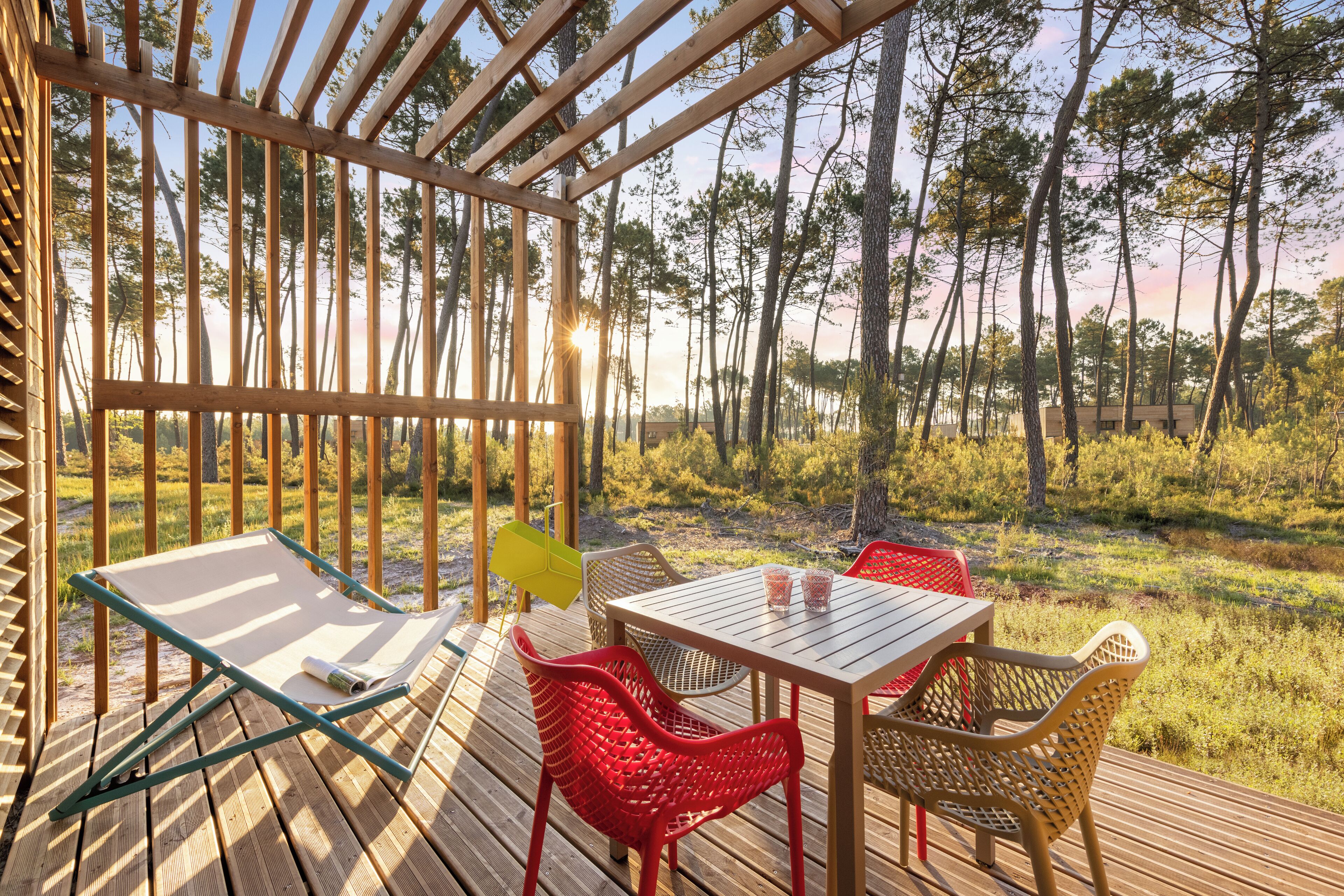 Una terraza de madera con mesa y sillas, con vistas a un área boscosa.