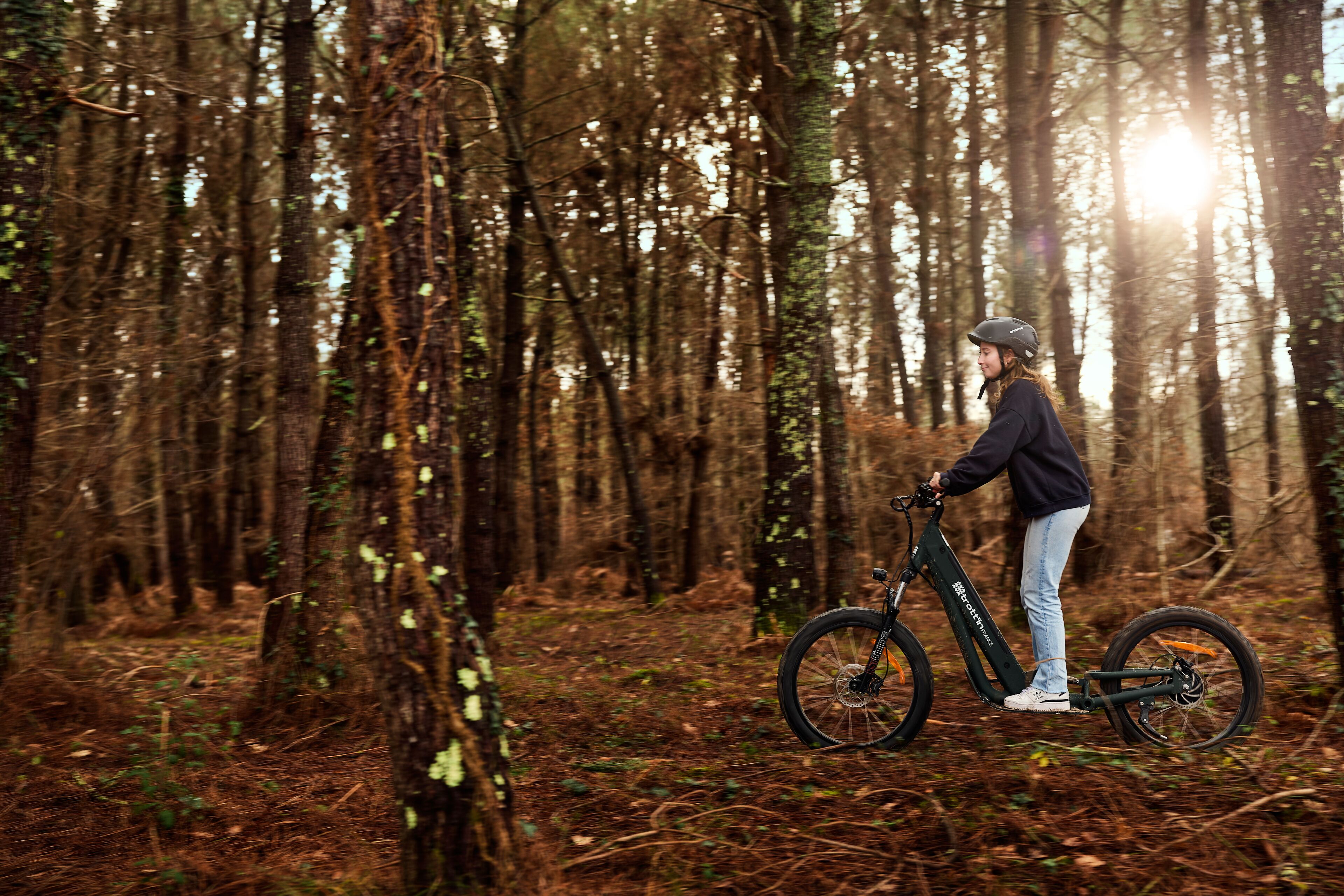 A person riding an electric bike in a forest.