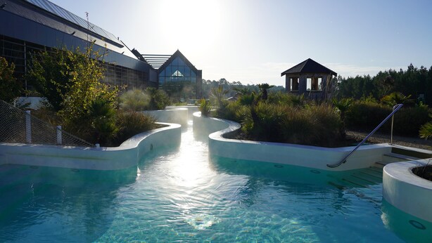 Une piscine à l’eau claire, entourée de verdure et agrémentée d’un belvédère.