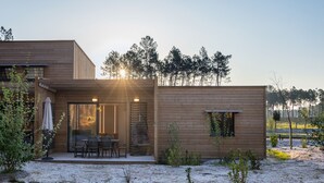 Une cabane moderne en bois dotée d’un patio, d’une table à manger et de chaises.