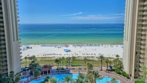 Een hoog hotel met uitzicht op een strand, inclusief zwembad en een terras.