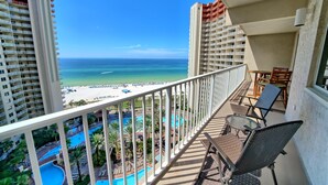 Een balkon met uitzicht op een strand en zwembad.
