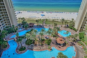 Un resort con una amplia zona de piscina, palmeras y vistas a la playa.