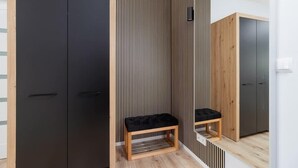 A modern room with a black wardrobe, a wooden bench, and a striped wall. - Modern Apartment | Balcony, Close to Center (Kraków)