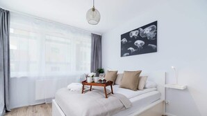 A modern bedroom with a bed, a bedside table, a window with curtains, and a wall-mounted artwork. - Modern Apartment | Balcony, Close to Center (Kraków)