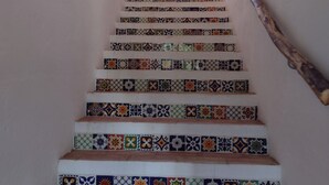 A staircase with colorful tiles and a small window at the top.