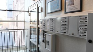 A hotel lobby with a glass door entrance, metal lockers, and a framed sign on the wall.