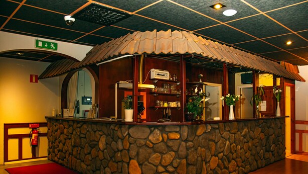 A stone bar area with a tiled ceiling, a fire extinguisher, and a red mat.