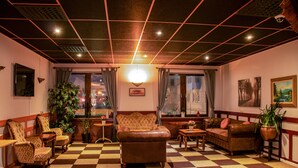A hotel lobby with a checkered floor, leather sofas, and potted plants.