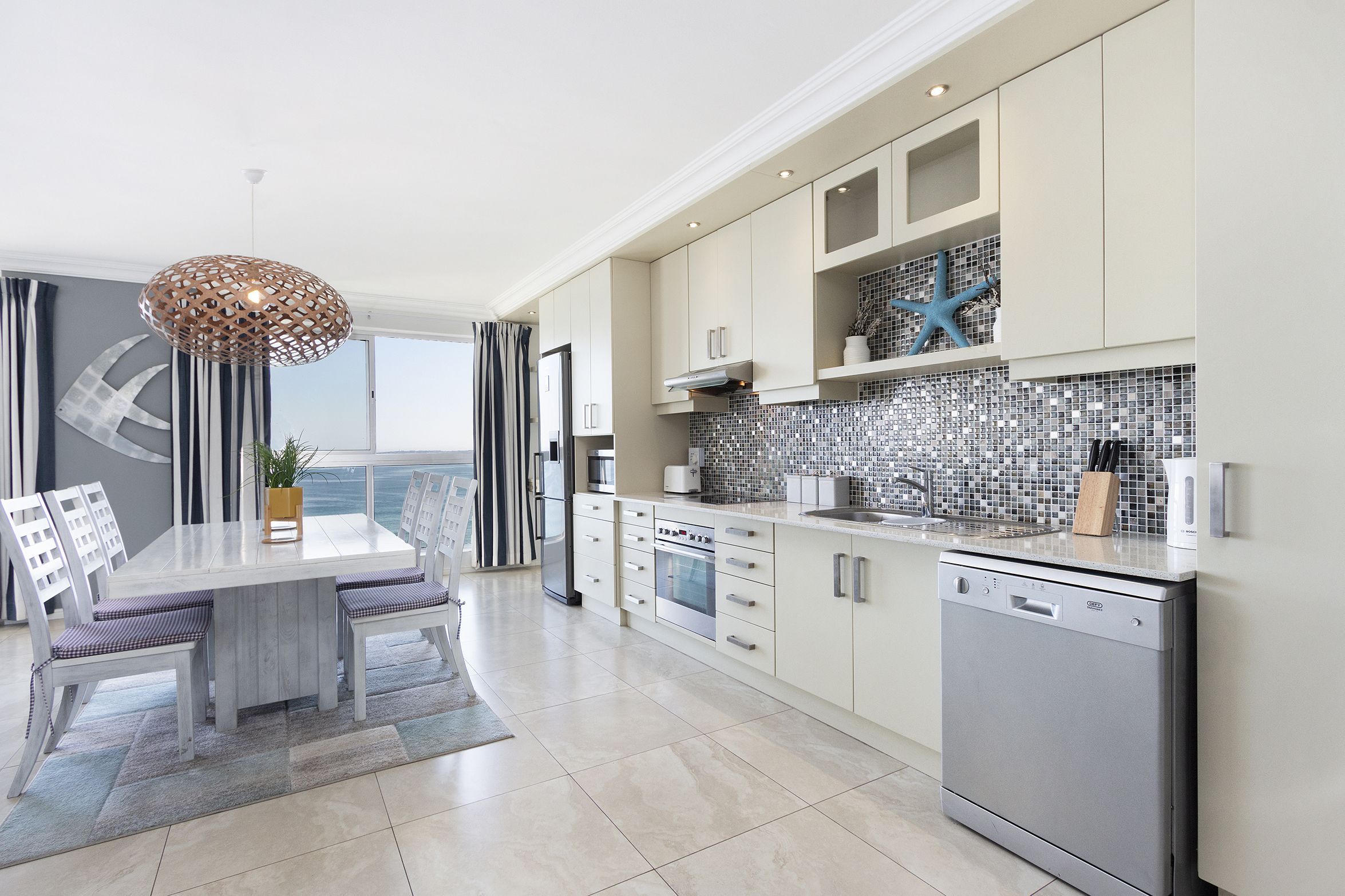 Een moderne keuken met een eethoek, met een grote tafel, stoelen en een vaatwasser.