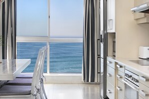 A modern kitchen with a large window overlooking the sea.