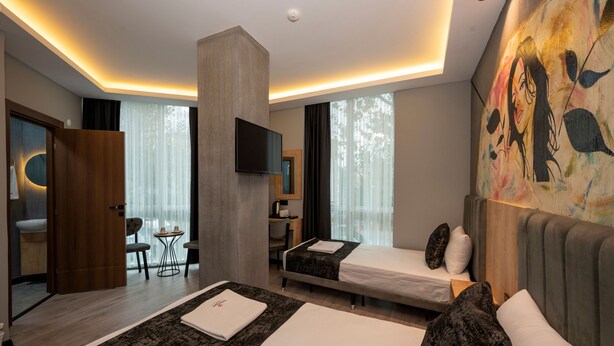 A modern hotel room with a large bed, a desk, a chair, and a TV. - Comfort Point (Istanbul)