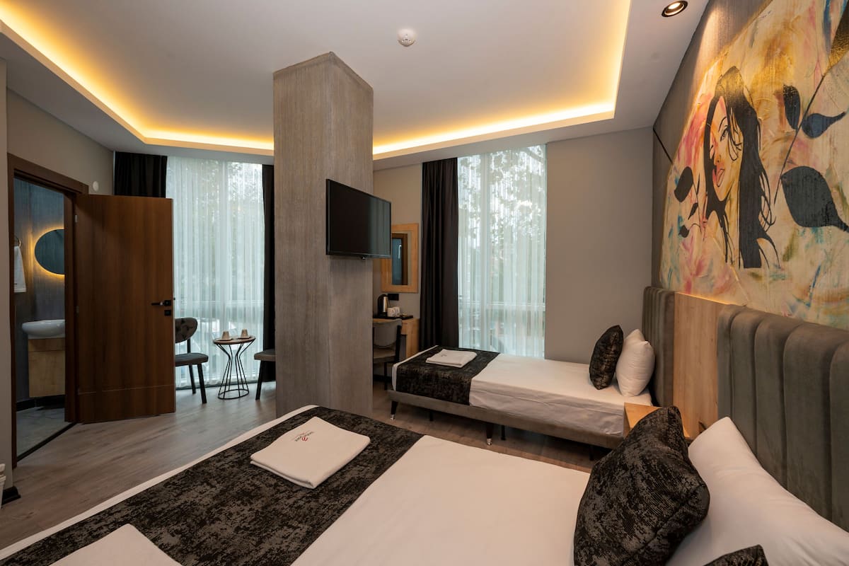 Et moderne hotelværelse med en stor seng, et skrivebord, en stol og et fjernsyn.