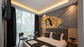 A modern hotel room with a large bed, a flat-screen TV, a painting on the wall, and a small table with chairs. - Comfort Point (Istanbul)