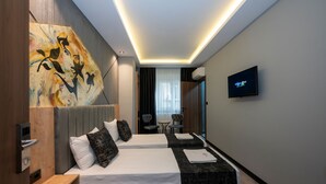A hotel room with two beds, a painting on the wall, a TV, and a small table with chairs. - Comfort Point (Istanbul)