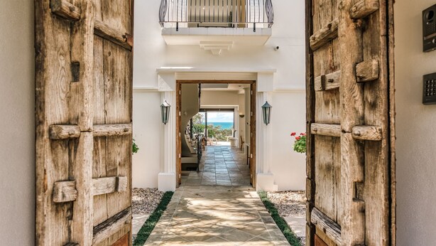 A hallway with rustic wooden doors leading to a balcony with a view of the sea. - Villa Sunshine - 200m to beach, ocean views, 5mins to Hastings St (Sunshine Beach)