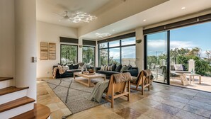 A spacious living room with a large sofa, coffee table, and a view of the outdoors through large windows. - Villa Sunshine - 200m to beach, ocean views, 5mins to Hastings St (Sunshine Beach)