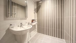 Un baño moderno con lavamanos, espejo y ducha.