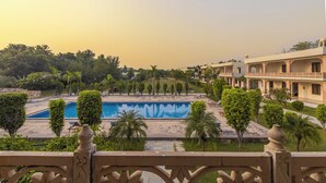 A swimming pool surrounded by greenery and a building with multiple balconies. - Ginger Ranthambore,Sawai Madhopur (Sawai Madhopur)