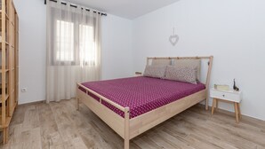 A bedroom with a wooden bed, a nightstand, a wardrobe, and a window with sheer curtains. - Holiday Home 'Casa La Puente' with A/C (Mijas)