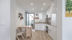 A compact kitchen with white cabinets, a wooden dining table, and a small window. - Holiday Home 'Casa La Puente' with A/C (Mijas)