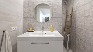 A bathroom with a white sink, a round mirror, and patterned tiles. - Holiday Home 'Casa La Puente' with A/C (Mijas)