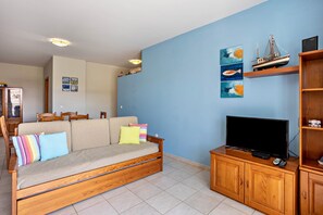 Un salon comprenant un canapé, un téléviseur, un meuble en bois et des œuvres d’art murales.