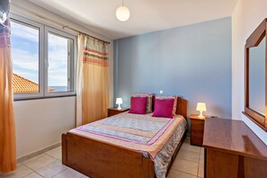 Une chambre à coucher avec un lit, deux tables de chevet avec des lampes, une fenêtre avec des rideaux et une vue sur le ciel.