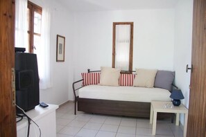 A bedroom with a bed, a bedside table, a lamp, a TV, and a window with curtains. - Apartment 'Maria's House 2' with Mountain View, Wi-Fi and Air Conditioning (Evias)
