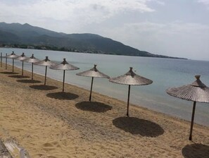 A beach with rows of thatched umbrellas and a calm sea. - Apartment 'Maria's House 2' with Mountain View, Wi-Fi and Air Conditioning (Evias)