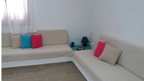A living room with a sofa, a coffee table, and a lamp. - Apartment 'Μaria's House 1' with Private Terrace, Shared Garden and Air Conditioning (Evias)