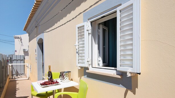 Ein Balkon mit Tisch für zwei Personen, einer Weinflasche und einer Platte mit Trauben.
