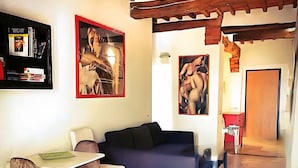A living room with a sofa, a dining table with chairs, and artwork on the walls.