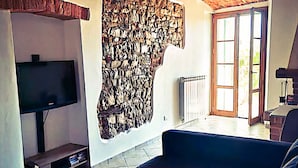 A living room with a stone wall, a television, a sofa, and a coffee table.