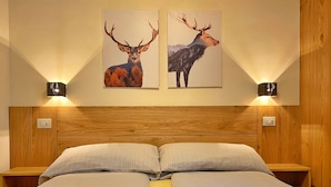 A double bed with two pillows, a wooden headboard, and two wall-mounted night lights. - Holiday Apartment Chalet Monteneve Toilà with Mountain View, Balcony & Wi-Fi (livigno)