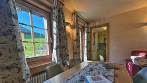 A dining area with a table, chairs, a laptop, and a book titled 'Apartamento Tolle'. - Holiday Apartment Chalet Monteneve Toilà with Mountain View, Balcony & Wi-Fi (livigno)