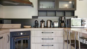 A kitchen with a built-in oven, a coffee maker, a kettle, a toaster, and a microwave. - Holiday Apartment Chalet Monteneve Neve with Mountain View, Shared Garden & Wi-Fi (Livigno)