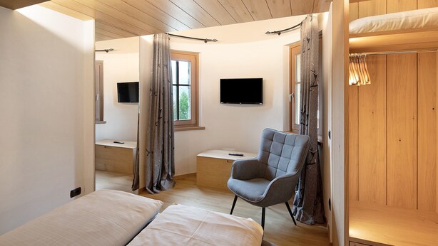 Un dormitorio con literas, un escritorio, una silla y un televisor.