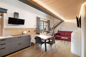 Une cuisine moderne avec un coin repas, un canapé rouge et un escalier.