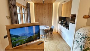 Una cocina moderna con armarios de madera, horno empotrado y comedor con mesa y sillas.